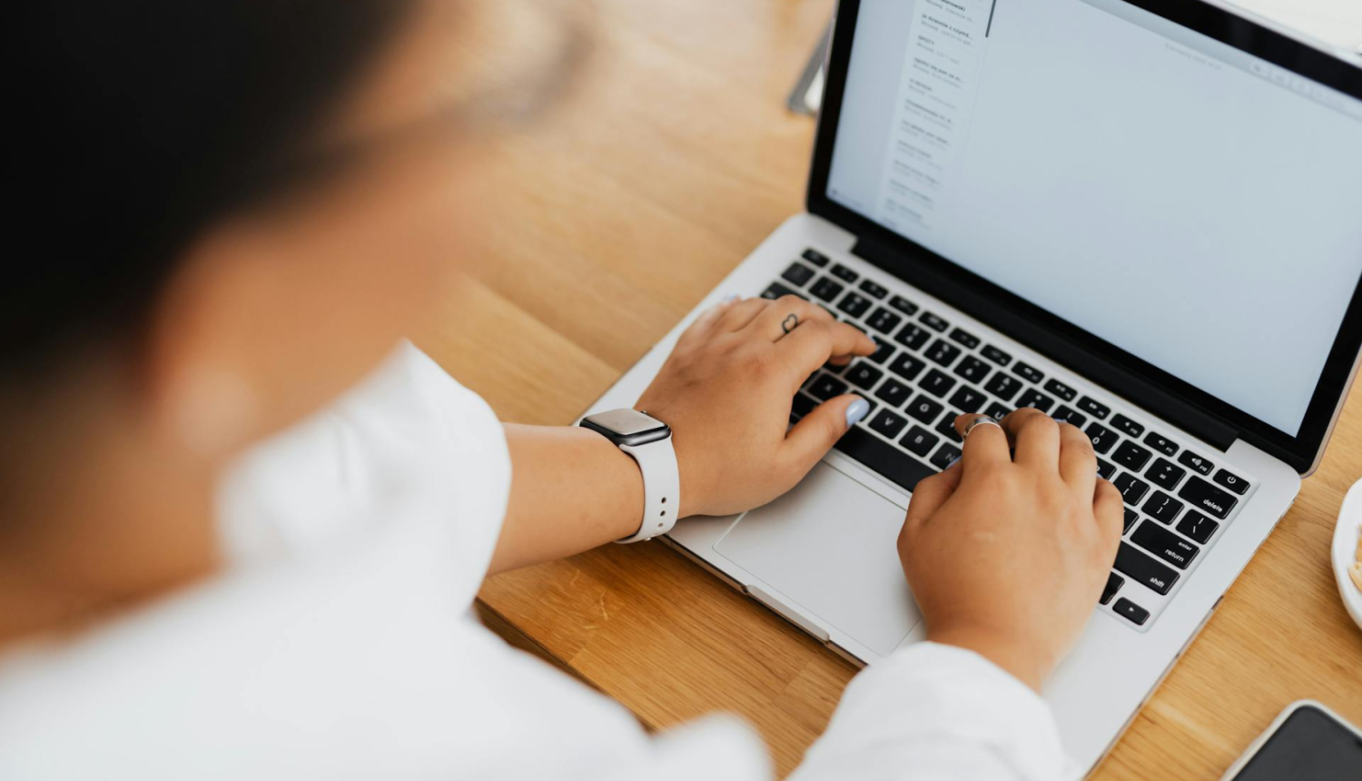 skats no augsās, cilvēks uzlicis rokas uz portatīvā datora klaviatūras